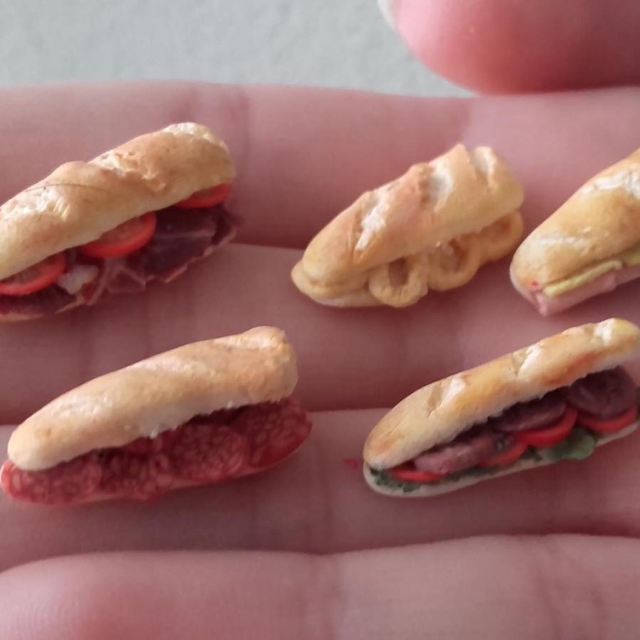 Bocadillos de calamares y otros en miniatura sostenidos por una mano