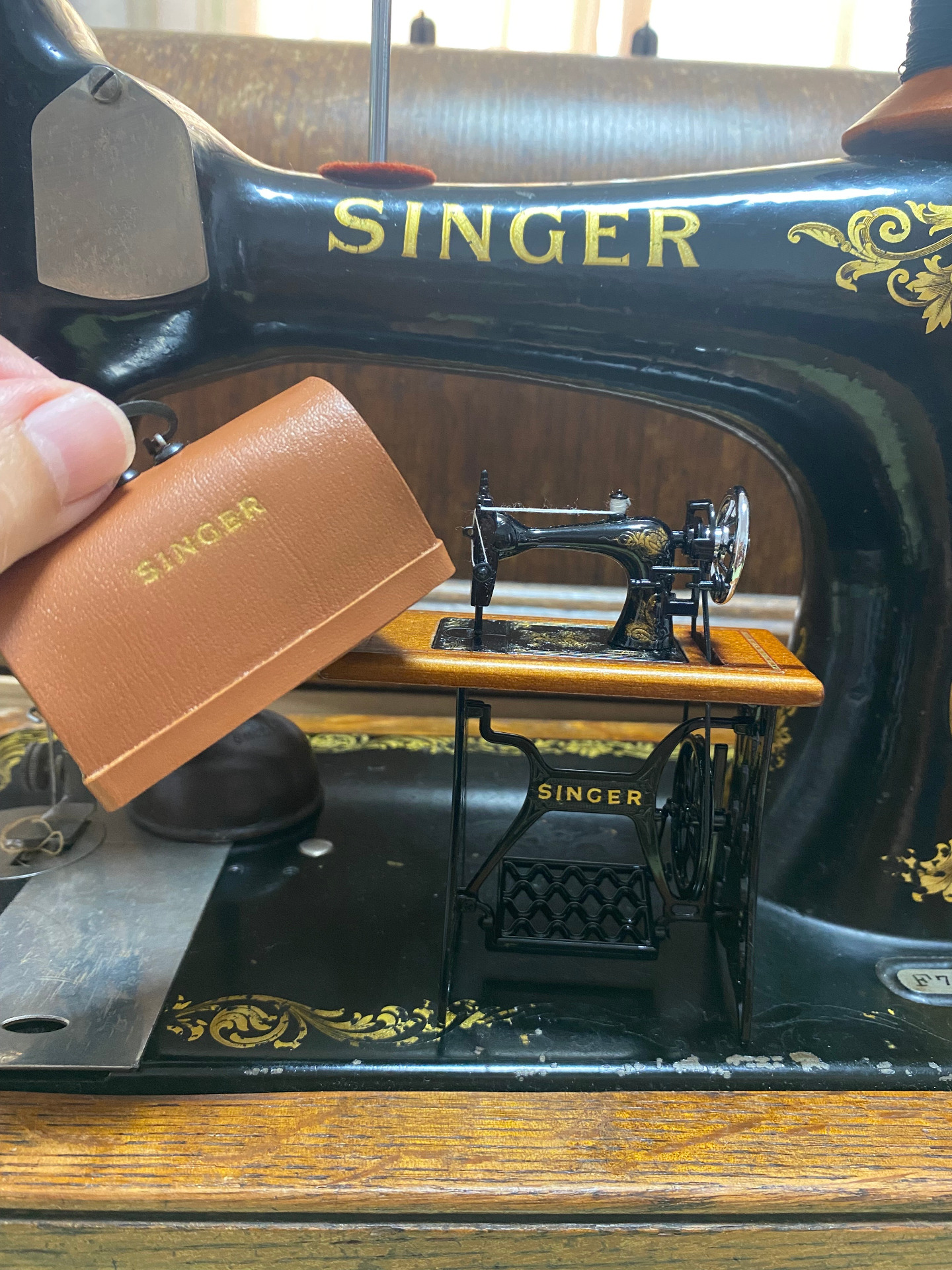 Máquina de coser miniatura sobre una real. 